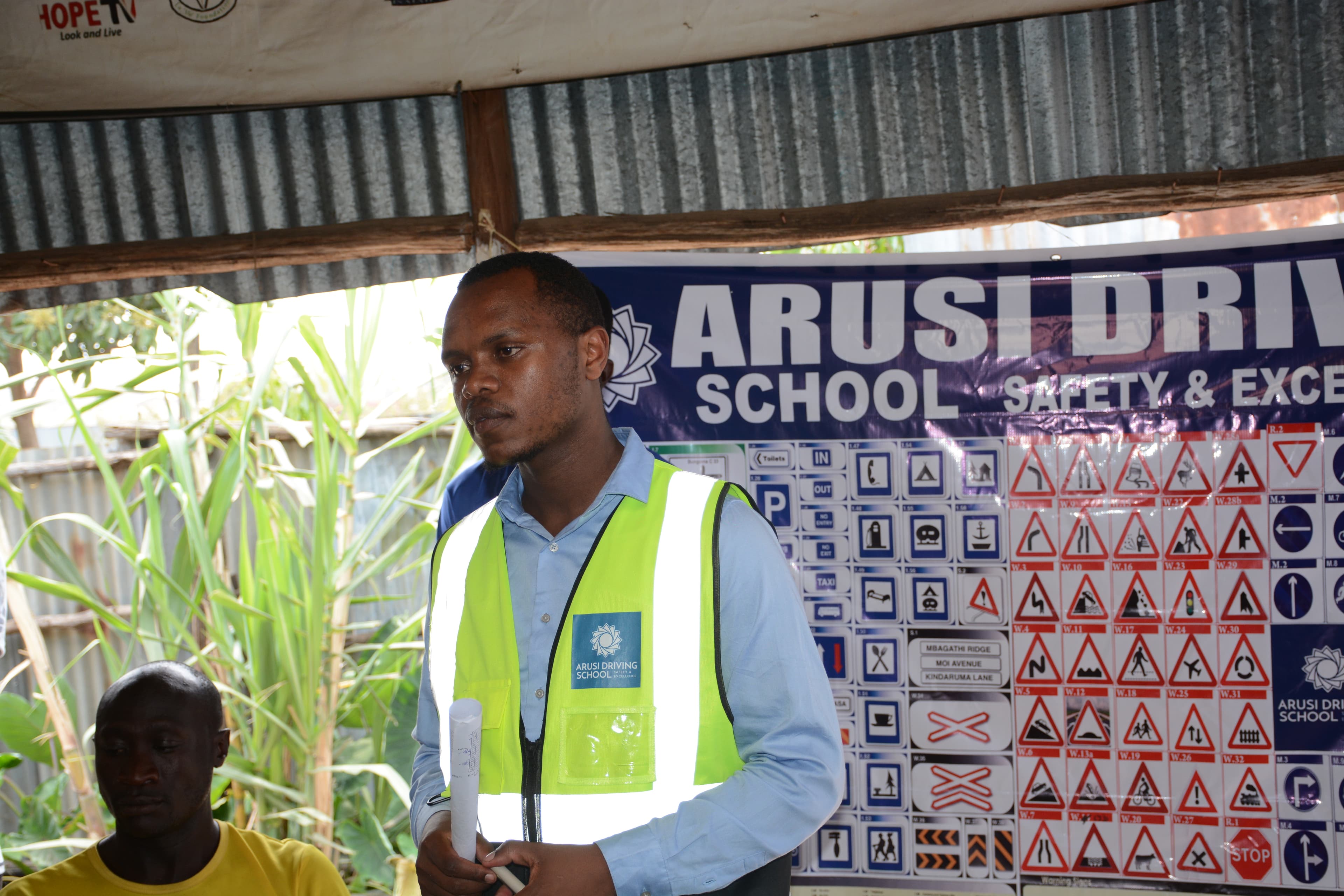 ARUSi Driving School instructor with road signs and training board.